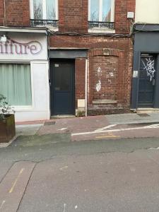 una strada vuota di fronte a un edificio di mattoni di Nuit magique jacuzzi, terrasse & lit motorisé - 008 a Rouen