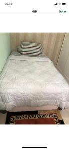 a bed in a small room with a white mattress at Ahnaf Guest House in Sunggal
