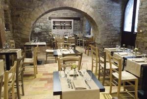 a restaurant with tables and chairs in a stone building at Il Vicoletto in Assisi