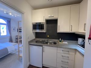 a kitchen with white cabinets and a sink at Melbury Rooms & Studios in Exeter