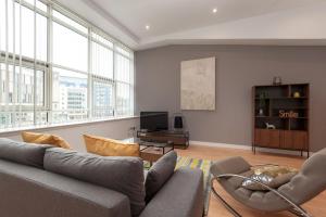 Una sala de estar con un sofá y sillas y ventanas. en Glasgow City Flats - Merchant City, en Glasgow