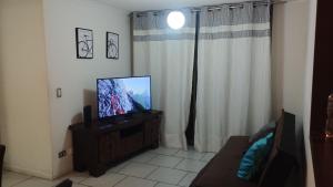 a living room with a flat screen tv on a cabinet at Departamento Playero 2 in Arica