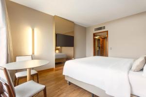 a hotel room with a bed and a table and a desk at Ouro Minas Hotel Belo Horizonte, Dolce by Wyndham in Belo Horizonte +86 photos