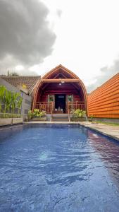 a large swimming pool in front of a building at Sayong Wooden House in Ubud
