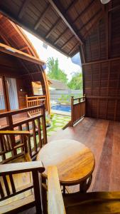 a room with a wooden table and chairs on a porch at Sayong Wooden House in Ubud