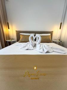 a bed with two swans towels on it at Elysian Escape Apartment in Sarandë