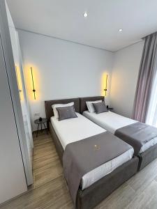 two beds in a hotel room with windows at Elysian Escape Apartment in Sarandë +37 photos