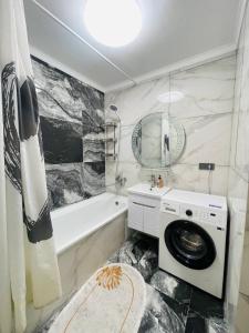 a bathroom with a washing machine and a bath tub at Уютные квартиры в Бишкеке in Bishkek