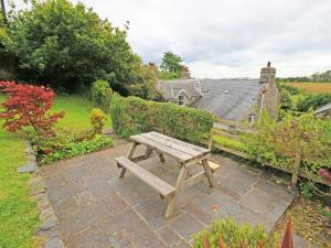 a wooden bench sitting on a brick patio at Y Stabl The Old Stable in Llanbedr
