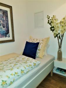 ein Bett mit einem blauen Kissen und einer Blumenvase in der Unterkunft Apartment Nordstern in Baabe