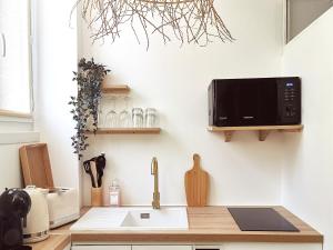 una cucina con forno a microonde appesa a un muro di La Suite Balinaise - Balnéo - Wifi - Netflix - Proche centre ville ad Auxerre