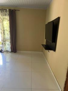 Una sala de estar con un televisor de pantalla plana en la pared. en Casa da Jessica, en Paraty