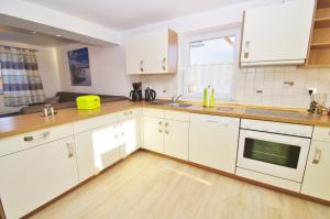 cocina con armarios blancos y suelo de madera en Ferienhaus Timm, en Kellenhusen