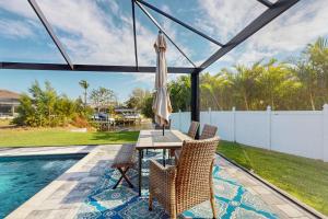 eine Terrasse mit Tisch und Stühlen neben einem Pool in der Unterkunft Oasis Haven in Cape Coral