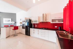 a kitchen with white cabinets and a black refrigerator at Beachfront Heaven Apartment Flic en Flac in Flic-en-Flac