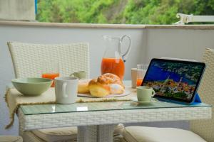a table with a laptop and a plate with donuts on it at Amalfi Coast - House Along the Amalfi Coast -FREE PARKING in Vietri sul Mare