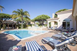 Un grupo de tumbonas y una piscina. en Villa Hera, en Vilamoura