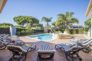 Un grupo de tumbonas y una piscina. en Villa Hera, en Vilamoura