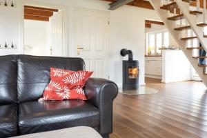 a leather couch in a living room with a wood stove at Großer Feldblick in Hinrichsdorf