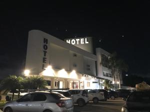 库里提巴Ipê Hotel Curitiba - Av das Torres的晚上，酒店停车场停满了车