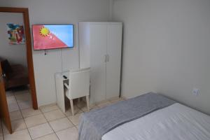 a bedroom with a bed and a desk and a tv at Apart Victoria in Vitória da Conquista