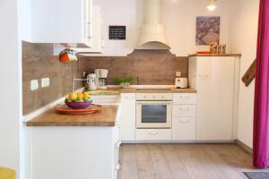a kitchen with white cabinets and a bowl of fruit on the counter at Ferienhaus Rotdorn - Haus Nord in Strukkamp auf Fehmarn