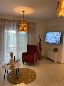 a living room with a red chair and a flat screen tv at NEW 2BD Aprt with Shared Rooftop Pool B3 in Athens