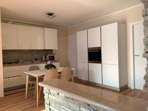 Una cocina con gabinetes blancos y una mesa con sillas. en Blue Lake, en Lovere