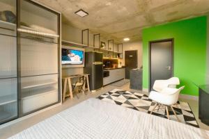 a living room with a green wall and a white chair at Apartamento Centro Moderno CA403 in Maringá
