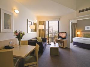 a hotel room with a bed and a living room at Oakbridge Hotel & Apartments Brisbane in Brisbane