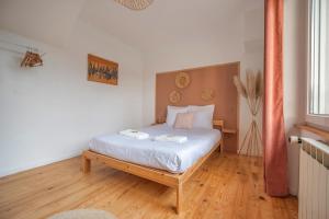 una camera da letto con un letto con lenzuola bianche e pavimenti in legno di Le Loft Triplex 200M2 avec billard au centre-ville a Épernay