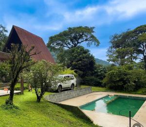 a vehicle parked next to a house with a swimming pool at Nature Cottage in Guapimirim
