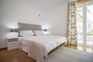 a white bedroom with a bed and a window at Villa Granada in Almancil +46 photos