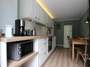 a kitchen with white cabinets and a wooden table at Ferienwohnung Haus am Berg, Lonau in Lonau
