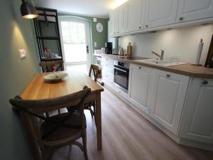 a kitchen with white cabinets and a wooden table at Ferienwohnung Haus am Berg, Lonau in Lonau