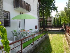 un patio con una mesa y una sombrilla verde en Oleander Holiday House, en Siófok