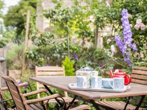 einen Holztisch mit Teetassen und Untertassen darauf in der Unterkunft April Cottage in Chipping Campden