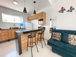 a kitchen with a bar with stools and a couch at Apartamento 5 Duplex 2 Suites Perto Praia do Mutá in Santa Cruz Cabrália