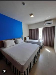 ein Schlafzimmer mit zwei Betten und einer blauen Wand in der Unterkunft Ondas Praia Resort in Porto Seguro