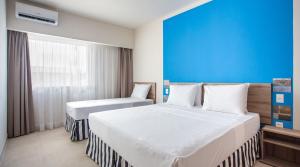 ein Hotelzimmer mit zwei Betten und einer blauen Wand in der Unterkunft Ondas Praia Resort in Porto Seguro