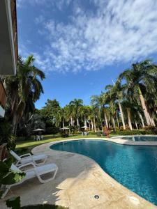 a swimming pool with a chair and palm trees at Finca San José, Los Naranjos Santa Marta in Santa Marta