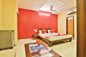 a bedroom with a bed and a red wall at Hotel O Sunrise in Vadodara