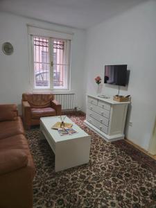 ein Wohnzimmer mit einer Couch, einem Fernseher und einem Couchtisch in der Unterkunft Apartment SG, Sarajevo in Sarajevo