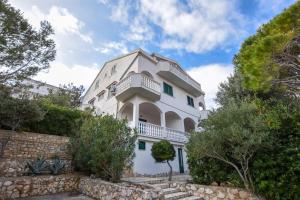ein weißes Gebäude mit einem Balkon darauf in der Unterkunft Rose Wind Apartments by Pag tours in Pag