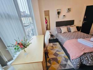 a bedroom with a bed and a table with a vase of flowers at Room 1 Shared House in L7 in Liverpool