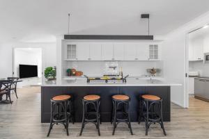 a kitchen with a black island with stools at Parkview for 8, Moss Vale, Southern Highlands in Moss Vale