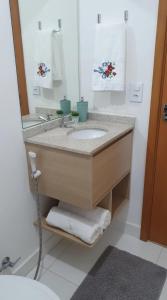 a bathroom with a sink and a mirror at Apto condomínio conforto e ótima localização in Lucas do Rio Verde