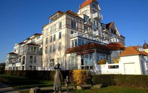a large white building with a woman standing in front of it at MeeresBlick - Urlaubstraum an der Ostsee in Kühlungsborn