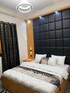 a bedroom with a large bed with a black padded headboard at Luxueuse petite chambre, salle de bain extérieure privée in Dakar