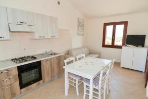 a kitchen with a table and a white table and chairs at Residence in Malamurì near Budoni, apartments 4 beds with private outdoor area in Budoni +7 photos